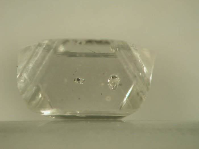Image 2: This diamond also contains two inclusions of colourless olivine. But this time they have had the morphology of the diamond imposed upon them, giving them more defined crystal faces and making them look less like a ‘bubble’. [Image taken by Dr Dan Howell, sample provided courtesy of Dr Jeff Harris, University of Glasgow.] 